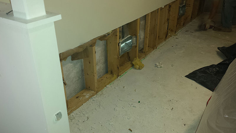 Cut sheetrock shows preparation to install french drain on finished wall | Before